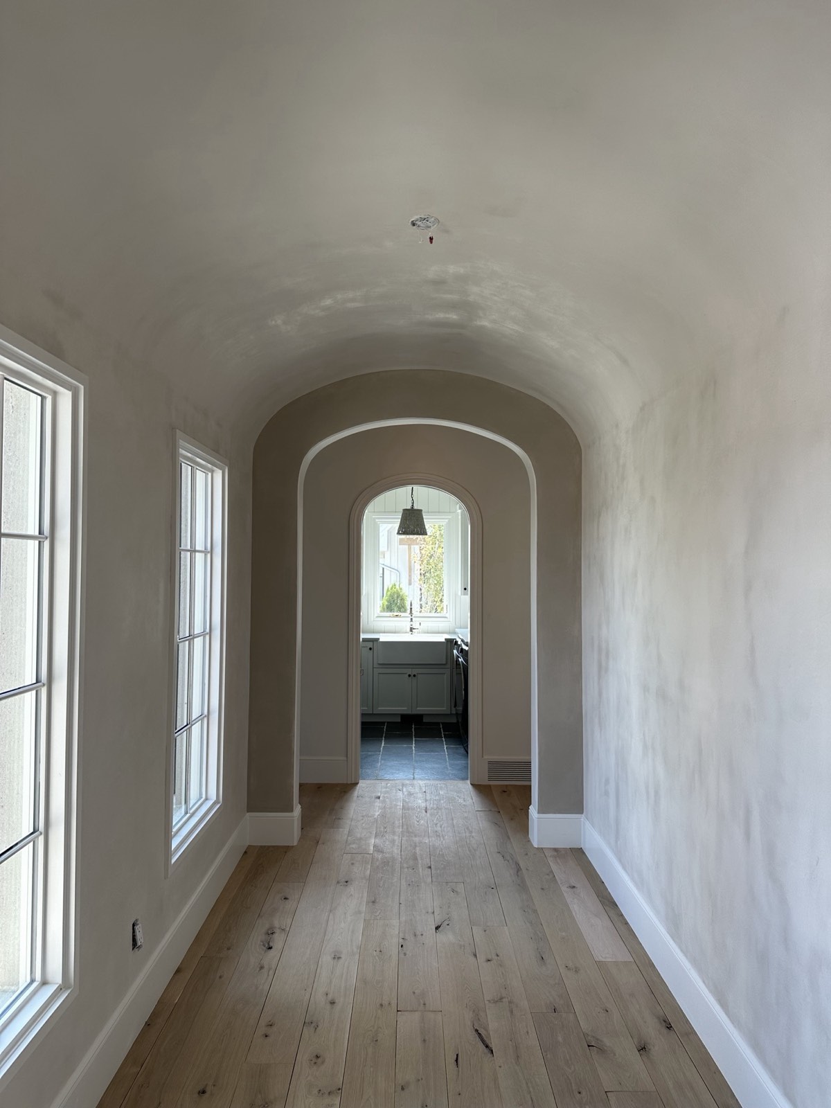 Plastered barrel-vault hallway with arched openings and tall windows