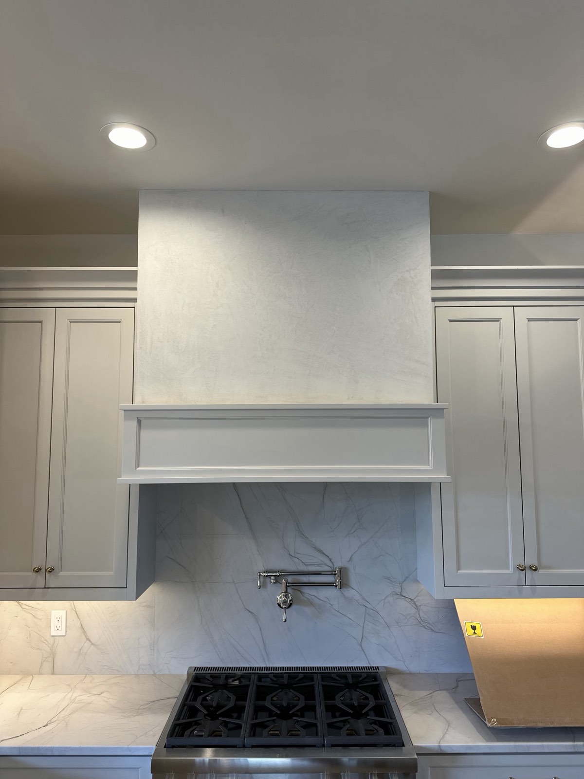 Smooth plaster range hood between kitchen cabinets