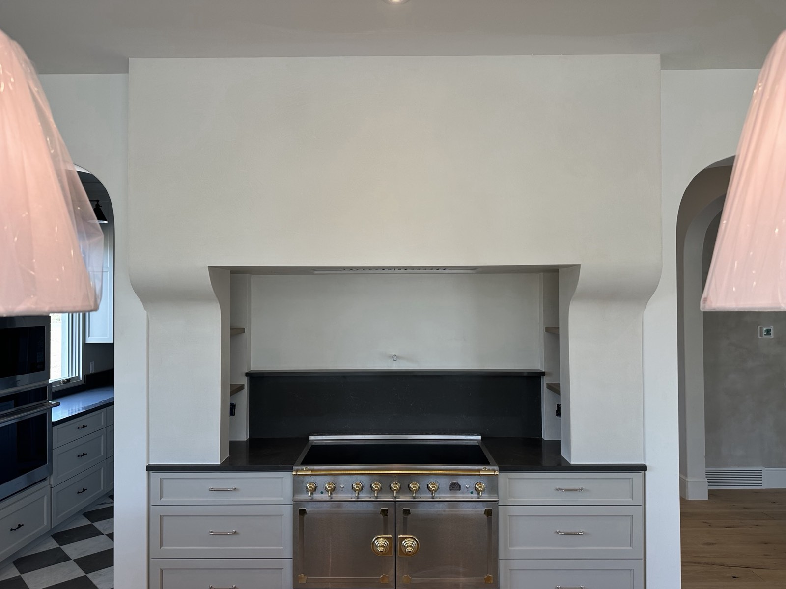 Sculpted plaster range hood with curved sides above a range