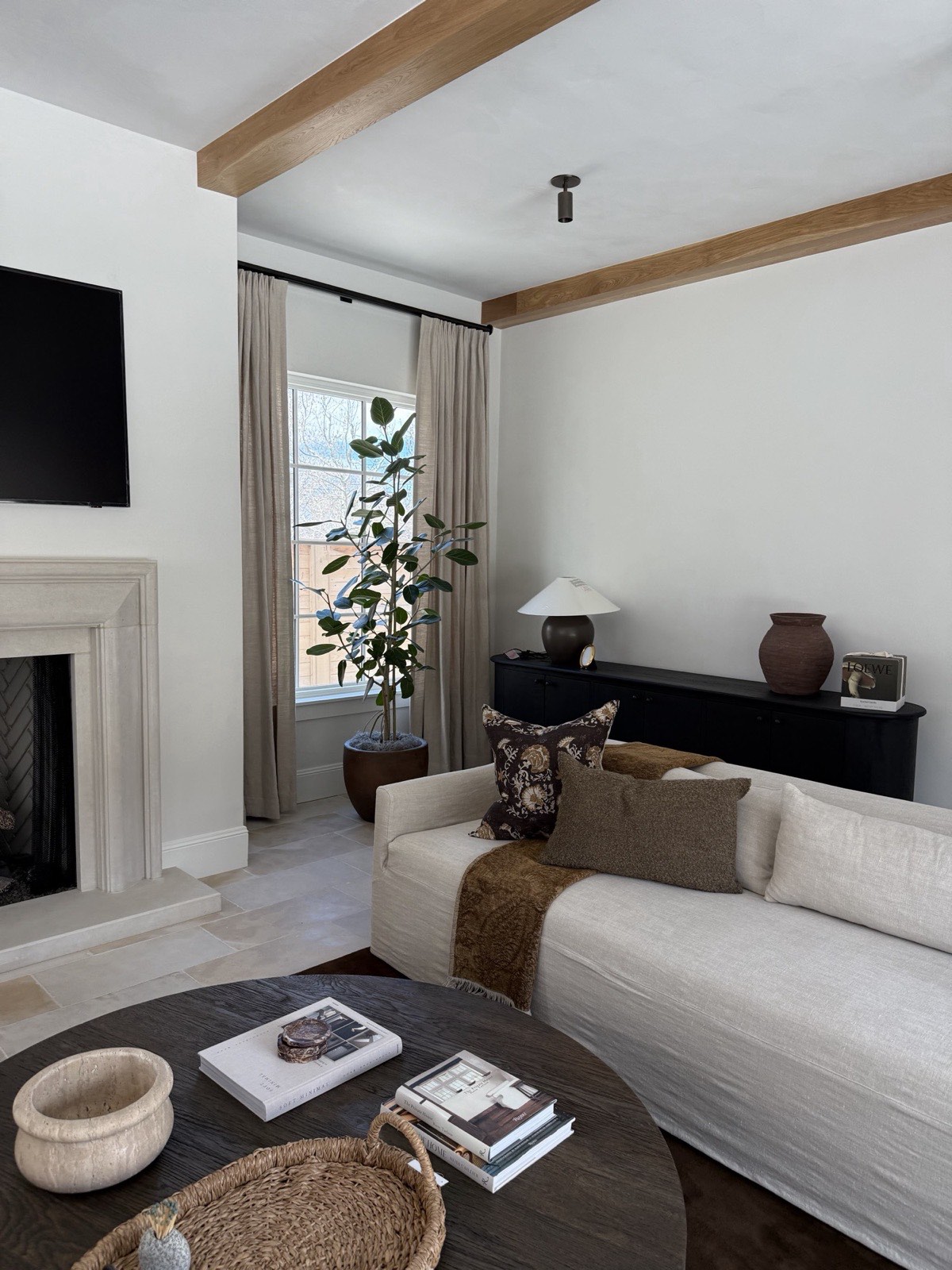 Pool house main room with fireplace, oak beams, and light plaster walls