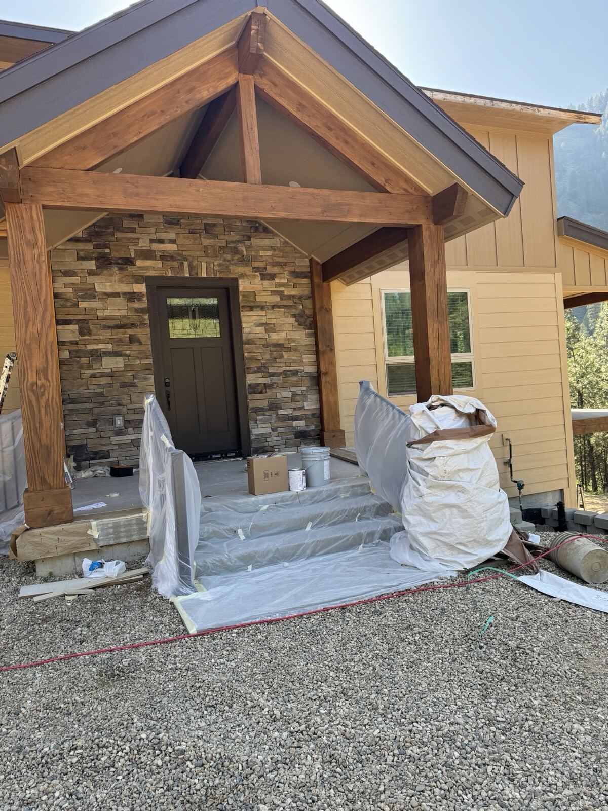 Freshly stained timber porch beams and posts, with steps and railings masked in plastic